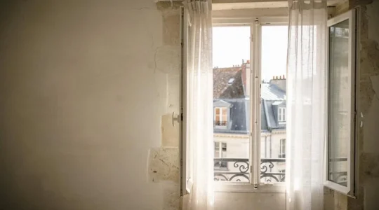 Fenêtre à la française grande ouverte laissant entrer la lumière naturelle dans un intérieur français rénové