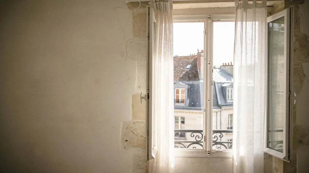 Fenêtre à la française grande ouverte laissant entrer la lumière naturelle dans un intérieur français rénové