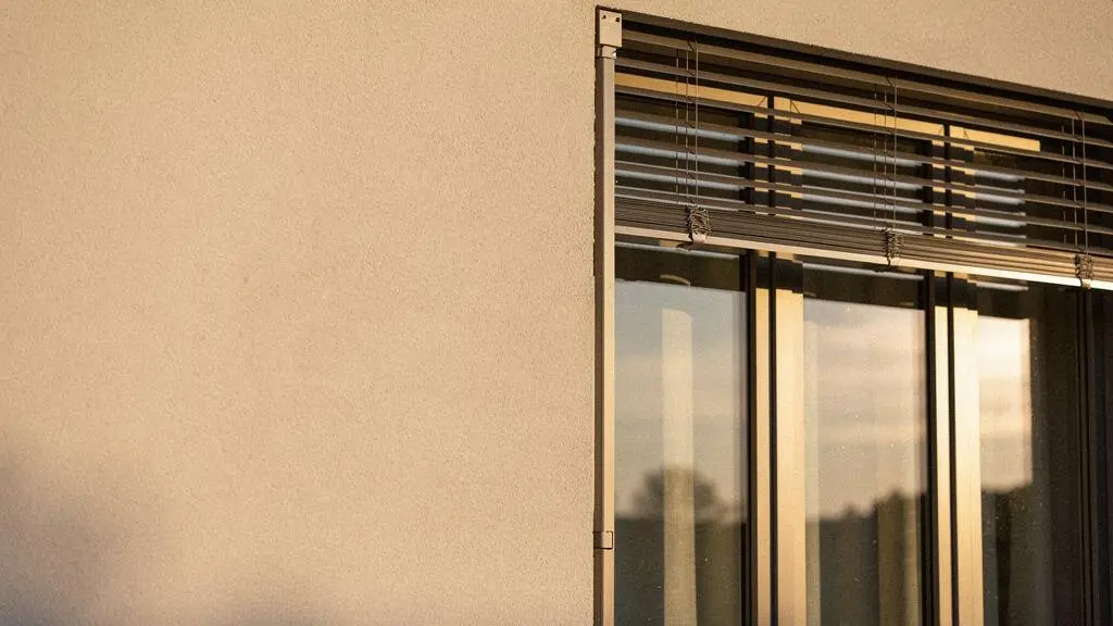 Façade d'une maison française contemporaine avec de larges fenêtres aluminium et une protection solaire extérieure, illustrant la performance et la durabilité des menuiseries