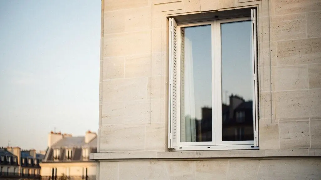 Fenêtre à double vitrage moderne sur un immeuble français, illustrant l'isolation thermique par gaz inerte entre les vitres