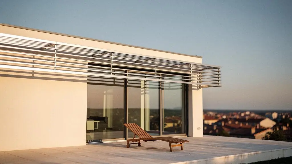 Façade contemporaine française équipée d'un brise-soleil à lames orientables filtrant la lumière du soleil couchant