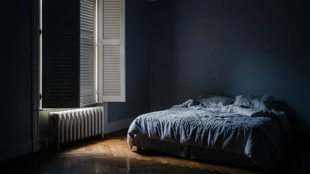 Chambre parisienne plongée dans l'obscurité totale grâce à des volets fermés, symbole d'une nuit de sommeil réparatrice