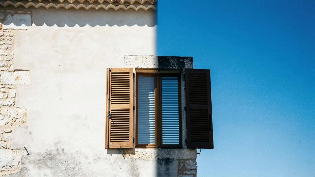 Facade d'une maison francaise avec volets mi-clos filtrant la lumiere intense d'une journee de canicule
