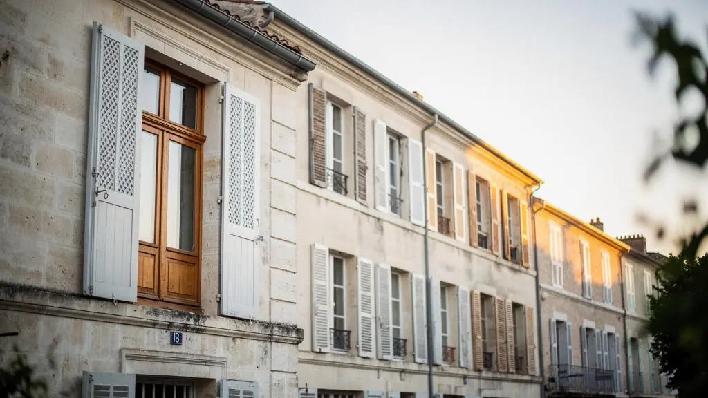 Facade d'une maison francaise de caractere avec une fenetre en bois ancienne restauree, symbole du dilemme entre renovation et remplacement des menuiseries