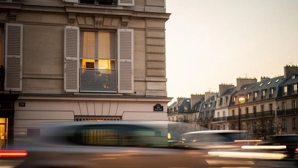 Fenêtre d'un appartement parisien avec store et volet fermés face à une rue animée, symbole de protection contre le bruit urbain